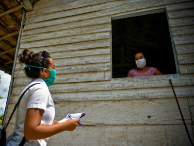 Une étudiante en médecine, à la recherche de possibles cas de coronavirus, parle avec une habitante de  Zaragoza, le 28 avril 2020 à Cuba - YAMIL LAGE [AFP/Archives]