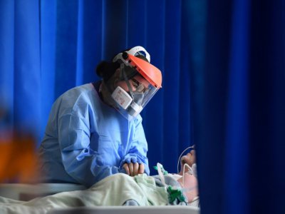 Une soignante réconforte un patient atteint par le Covid-19 dans un hôpital de Cambridge, le 5 mai 2020 au Royaume-Uni - Neil HALL [POOL/AFP]