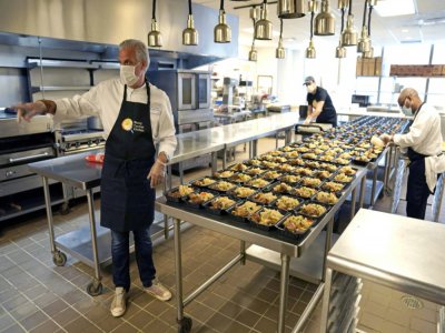 Eric Ripert, chef et co-propriétaire du restaurant étoilé new-yorkais Le Bernardin, avec deux employés préparant des repas en barquettes pour des soignants, le 6 mai 2020 à New York - TIMOTHY A. CLARY [AFP]