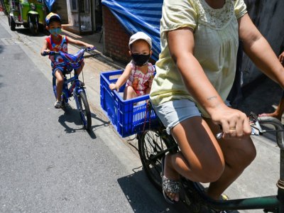 Une famille à vélo dans une rue de Bangkok, le 7 mai 2020 - Romeo GACAD [AFP]