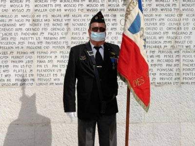 Un vétéran tient le drapeau français devant le monument aux morts à Nice, le 8 mai 2020 pour célébrer la fin de la Seconde guerre mondiale - VALERY HACHE [AFP]