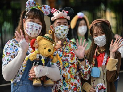 Des visiteurs portant des masques attendent d'entrer dans le Disneyland de Shanghai qui rouvre le 11 mai 2020 - Hector RETAMAL [AFP]