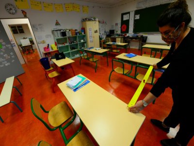 Une enseignante mesure la distance entre les tables dans une salle de classe, le 11 mai 2020 à Cenon, près de Bordeaux - MEHDI FEDOUACH [AFP]
