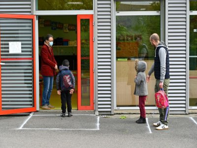 Un enseignant portant un masque de protection accueille un enfant dans sa classe tandis qu'un autre attend à distance, le 12 mai 2020 à l'école publique Champ l'Evêque de Bruz - Damien MEYER [AFP]