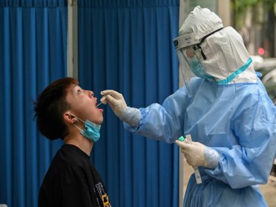 Un soignant effectue un prélèvement dans le cadre d'un dépistage du nouveau coronavirus, à Wuhan, le 14 mai 2020. - Hector RETAMAL [AFP]