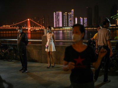 Des habitants de Wuhan portant des masques de protection dansent le long du fleuve Yangtsé, en Chine, le 13 mai 2020. - Hector RETAMAL [AFP]