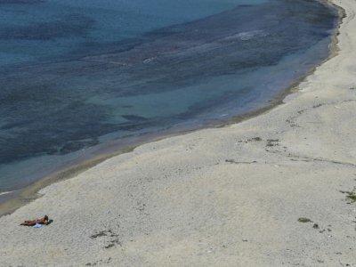 Une femme profite seule du soleil à la plage à Myconos, le 12 mai 2020 où les touristes ont déserté à cause de la crise sanitaire mondiale - ARIS MESSINIS [AFP]