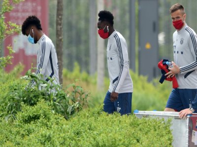 Les joueurs du Bayern Munich, Kingsley Coman, Davies Alphonso et le gardien Christian Fruechtl portent un masque à leur arrivée à l'entraînement, à Munich, le 13 mai 2020 - Christof STACHE [AFP/Archives]