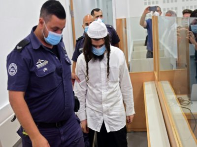 Le colon israélien Amiram Ben-Ouliel escorté par la police au tribunal de Lod, le 18 mai 2020 en Israêl - Avshalom SASSONI [POOL/AFP]