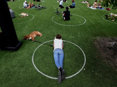 Des personnes pratiquent la distanciation sociale dans des cercles tracés sur la pelouse dans un parc de Brooklyn, le 17 mai 2020 à New York - Johannes EISELE [AFP]