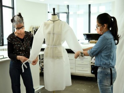 Deux couturières chez Louis Vuitton confectionnent un modèle de blouse qui doit etre porté par des infirmières, dans leur atelier à Paris, le 10 avril 2020 - BERTRAND GUAY [AFP/Archives]