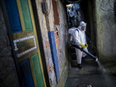 Un volontaire désinfecte une rue dans la favela Santa Marta de Rio de Janeiro le 20 avril 2020 dans le cadre de la lutte contre le coronavirus - Mauro PIMENTEL [AFP]