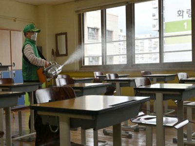 Un employé désinfecte une salle de classe dans un lycée de Séoul le 19 mai 2020 - Jung Yeon-je [AFP]