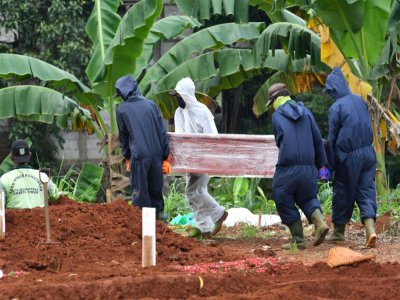 Des fossoyeurs portent le cercueil d'une personne décédée du coronavirus au cimetière de Pondok Ranggon, le 6 mai 2020 à Jakarta, en Indonésie - ADEK BERRY [AFP]