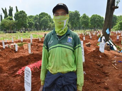Le fossoyeur Junaidi Hakim devant des tombes de personnes décédées du coronavirus au cimetière de Pondok Ranggon, le 6 mai 2020 à Jakarta, en Indonésie - ADEK BERRY [AFP]