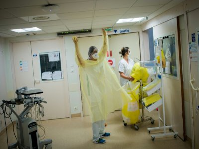 Une infirmière enfile sa surblouse de protection avant d'entrer dans la chambre d'un patient malade du coronavirus dans l'unité de soins intensifs du Chu DE Nantes, le 19 mai 2020 - Loic VENANCE [AFP]