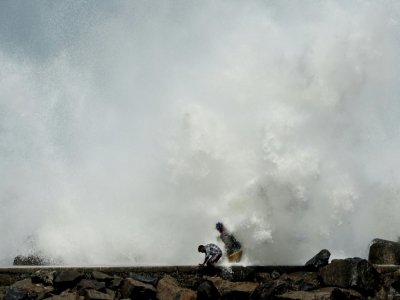 Deux hommes sur la jetée, près d'un brise-lames, à Chennai, sur le golfe du Bengale, avant l'arrivée du cyclone Amphan, le 19 mai 2020 - Arun SANKAR [AFP]