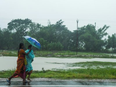 Deux femmes marchent sur la route avant l'arrivée du cyclone Amphan, à Midnapore, en Inde, sur le golfe du Bengale, le 20 mai 2020 - Dibyangshu SARKAR [AFP]