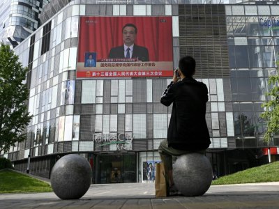 Un homme regarde la transmission en direct de la session inaugurale du parlement chinois à Pékin, le 22 mai 2020 - WANG ZHAO [AFP]