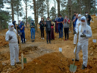 Quelques membres de la famille se recueillent devant la tombe d'un proche décédé du coronavirus au cimetière d'Istanbul, le 21 mai 2020 en Turquie - BULENT KILIC [AFP]
