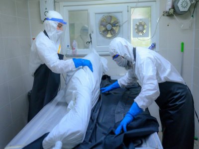 Des personnels funéraires en combinaison de protection préparent le corps d'une personne décédée du coronavirus à la morgue du cimetière d'Istanbul, le 21 mai 2020 en Turquie - BULENT KILIC [AFP]