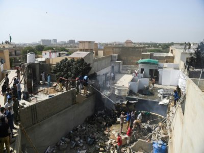 Des équipes de secours arrosent les débris d'un avion de la compagnie Pakistan International Airlines qui s'est écrasé sur un quartier résidentiel de Karachi, le 22 mai 2020 au Pakistan - Asif HASSAN [AFP]