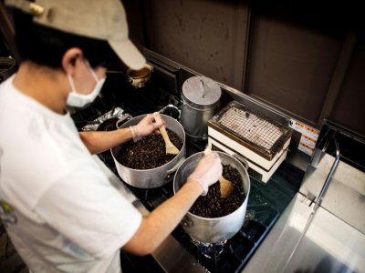 Yuta Shinohara cuit les criquets, ingrédient qui sert à parfumer le bouillon de ses ramen, à Tokyo le 13 mai 2020 - Behrouz MEHRI [AFP]