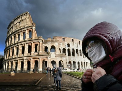Un homme portant un masque de protection passe devant le Colisée à Rome le 7 mars 2020 - Alberto PIZZOLI [AFP]