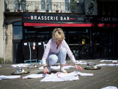 Une femme étale des dizaines de blouses blanches, toques et plateaux sur une place face à un restaurant à Nantes, ouest, le 27 mai 2020, pour protester contre les conséquences du confinement - Loic VENANCE [AFP]