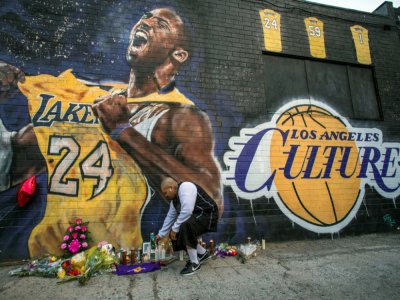 Un fan allume une bougie devant une fresque représentant Kobe Bryant, le 26 janvier 2020 à Los Angeles - Apu GOMES [AFP/Archives]