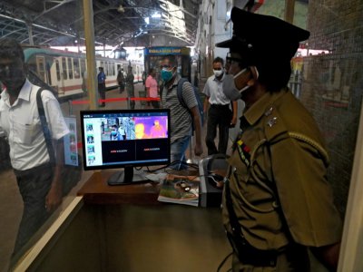 Un membre de la sécurité contrôle la température des voyageurs dans une gare de Colombo, le 26 mai 2020 au Sri Lanka - Ishara S. KODIKARA [AFP/Archives]