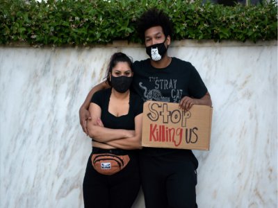 Un couple pose avec un écriteau qui demande "Arrêter de nous tuer", à Los Angeles le 27 mai 2020, après la mport de George Floyd, un Afroaméricain asphixié par la police lors d'une interpellation - Agustin PAULLIER [AFP]
