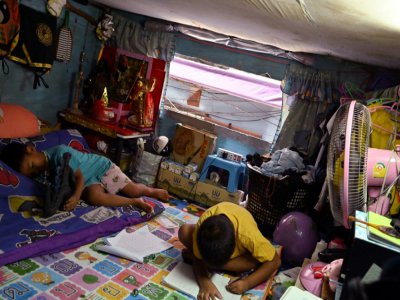 Les deux enfants de la famille Noidee dans l'unique pièce qu'ils habitent dans un bidonville de Bangkok, le 28 mai 2020 en Thaïlande - Romeo GACAD [AFP]
