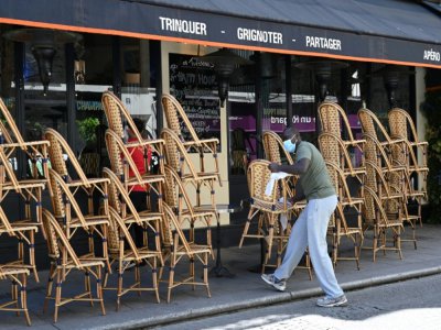 Un employé nettoie les chaises avant la réouverture des terrasses des cafés, bars et restaurants, le 30 mai 2020 à Paris - BERTRAND GUAY [AFP]