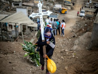 Une femme porte une croix lors des funérailles d'un proche au cimetière de Nueva Esperanza, près de Lima, le 30 mai 2020 au Pérou - ERNESTO BENAVIDES [AFP]