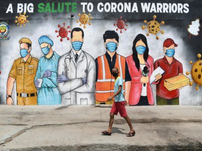 Un homme passe dant une fresque murale qui rend hommage aux "guerriers du corona", le 31 mai à New Delhi - Sajjad  HUSSAIN [AFP]