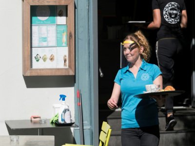 Une serveuse avec une visière de protection, à la terrasse d'un café à Mulhouse, le 2 juin 2020 - SEBASTIEN BOZON [AFP]