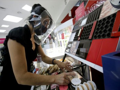 Une vendeuse équipée d'une visière et d'un masque de protection dans une boutique de cosmétiques, le 1er juin 2020 à Guadalajara, au Mexique - Ulises RUIZ [AFP]