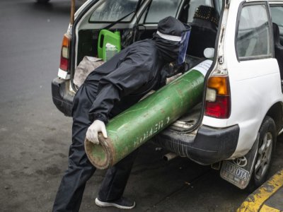 Un homme charge dans une voiture une bouteille d'oxyène vide pour aller la remplir, le 3 juin 2020 à Lima, au Pérou - Ernesto Benavides [AFP]