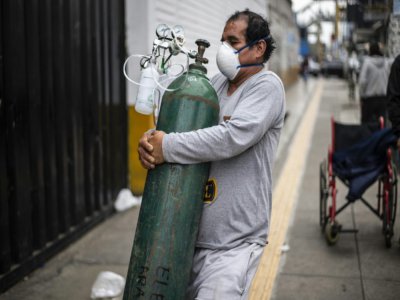 Un homme porte une bouteille d'oxygène pleine destinée à un proche atteint par le coronavirus, le 3 juin 2020 à Lima, au Pérou - Ernesto Benavides [AFP]