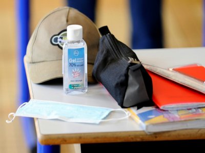 Masque et gel hydroalcoolique sur le bureau d'un élève dans une salle de classe à Villers-les-Nancy, le 12 mai 2020 - JEAN-CHRISTOPHE VERHAEGEN [AFP/Archives]