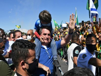 Le président brésilien Jair Bolsonaro porte le fils d'un de ses partisans lors d'un rassemblement à Brasilia le 31 mai 2020 - EVARISTO SA [AFP]