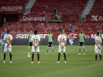 Les joueurs de Séville (blanc) et du Betis (vert) observent une minute de silence en hommage aux victimes du coronavirus, le 11 juin 2020 à Séville - CRISTINA QUICLER [AFP]