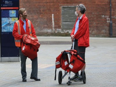 Des employés de la poste portent des masques de protection pendant leur tournée à Leeds, dans le nord de l'Angleterre, le 2 mai 2020 - Lindsey Parnaby [AFP/Archives]