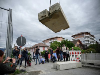 Journalistes et passants observent l'opération de retrait d'un bloc de béton qui fermait la frontière entre France et Suisse, le 14 juin 2020 à Thonex, en France - Fabrice COFFRINI [AFP]