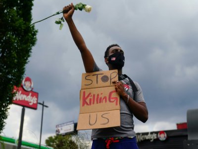 Un manifestant tient une pancarte implorant "arrêtez de nous tuer", devant le restaurant près duquel est mort l'avant-veille Rayshard Brooks, un Afro-Américain tué par un policier blanc, à Atlanta le 14 juin 2020 - Elijah Nouvelage [AFP]