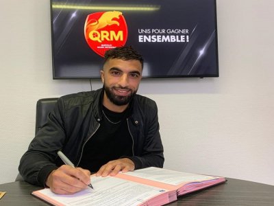 Tout sourire, le joueur de foot Yassine Bahassa signe son contrat le liant à Quevilly Rouen Métropole. Il s'agit par ailleurs de son premier contrat professionnel. - QRM