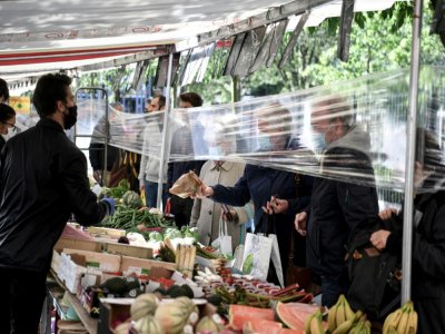 Un film plastique entre des clients et des vendeurs de fruits et légumes sur un marché à Paris en mai 2020 - ALAIN JOCARD [AFP/Archives]