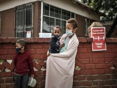 Un enfant porte un autre enfant dans ses bras pendant une distribution d'aide, Ã  Johannesburg, le 19 mai 2020 - MARCO LONGARI [AFP]