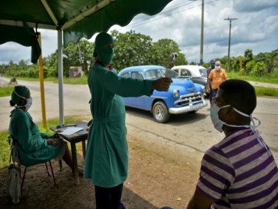 Une employée de la Santé contrôle la température d'un Cubain à San José de las Lajas, le 18 juin 2020, à l'est de La Havane - YAMIL LAGE [AFP]